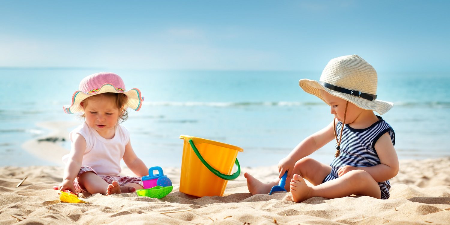 Babygirl and babyboy sitting on the beach